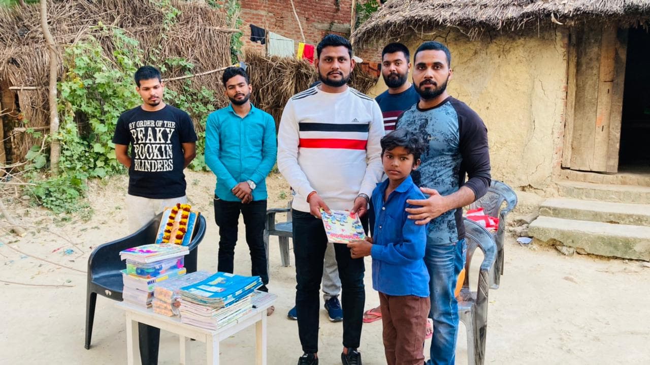 Volunteers presenting books and supplies to a family at their home in a village